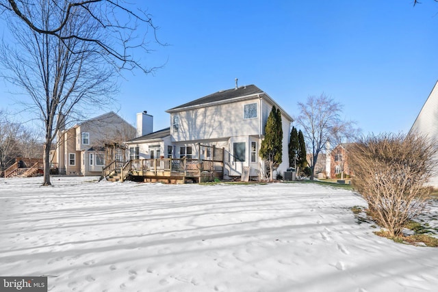 snow covered rear of property with a wooden deck