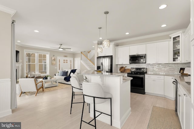 kitchen with hanging light fixtures, white cabinetry, appliances with stainless steel finishes, and light stone countertops