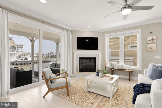 living room with wood-type flooring, ornamental molding, and ceiling fan