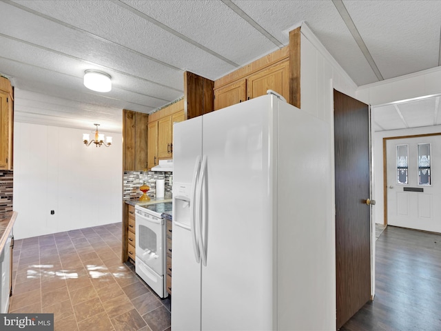 kitchen featuring a textured ceiling, hanging light fixtures, a notable chandelier, white appliances, and backsplash