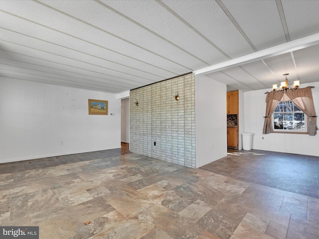 unfurnished room featuring brick wall and a notable chandelier