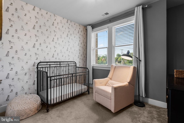 carpeted bedroom featuring visible vents, a crib, baseboards, and wallpapered walls