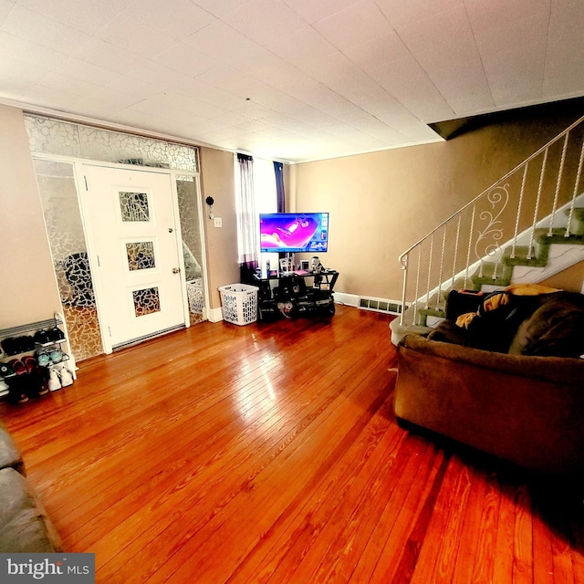 living area featuring visible vents, stairway, and wood finished floors