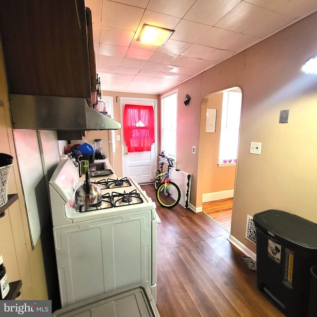 kitchen featuring dark wood-style floors, arched walkways, baseboards, and white gas range