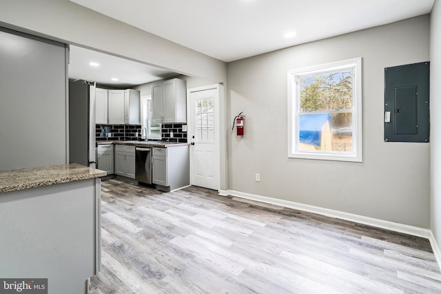 kitchen featuring gray cabinetry, light wood-type flooring, stainless steel dishwasher, electric panel, and decorative backsplash