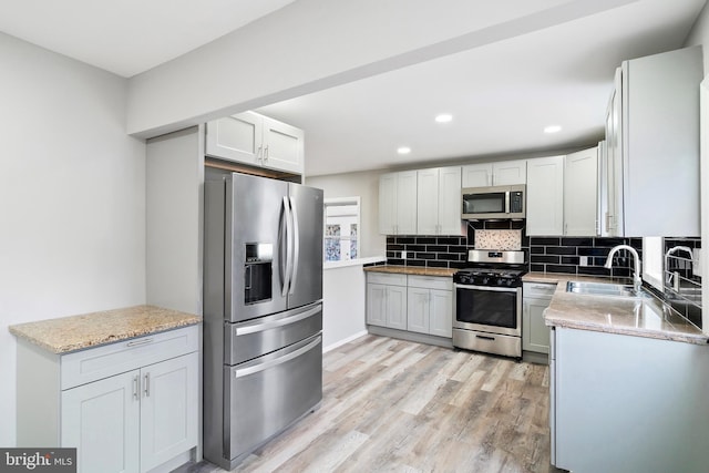 kitchen with white cabinetry, appliances with stainless steel finishes, sink, and decorative backsplash