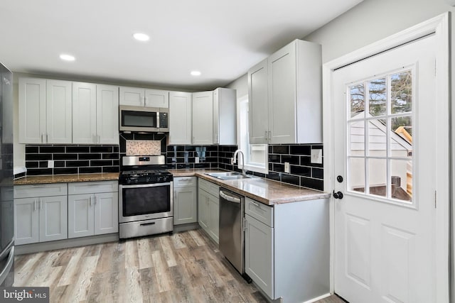 kitchen with sink, light hardwood / wood-style flooring, appliances with stainless steel finishes, gray cabinetry, and tasteful backsplash