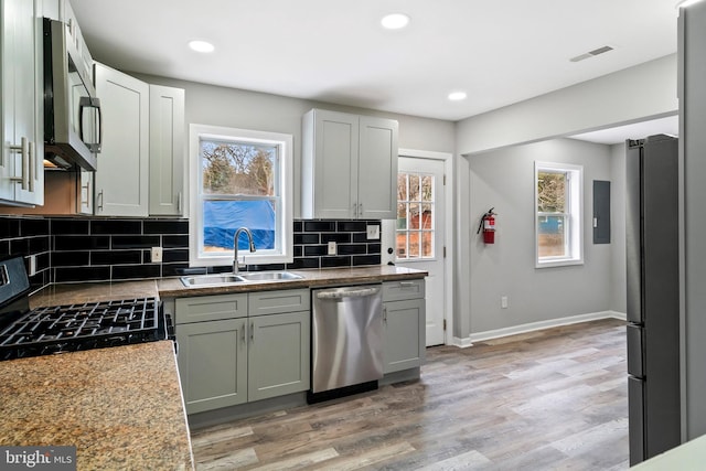 kitchen featuring appliances with stainless steel finishes, tasteful backsplash, sink, light stone counters, and light wood-type flooring