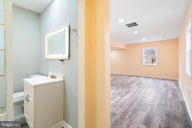 bathroom with hardwood / wood-style flooring, vanity, and toilet