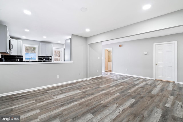 unfurnished living room featuring sink and hardwood / wood-style flooring