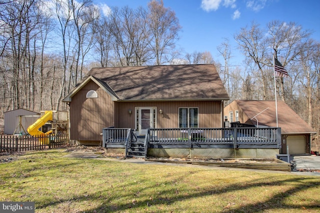 rustic home featuring a front lawn, a playground, a wooden deck, and fence