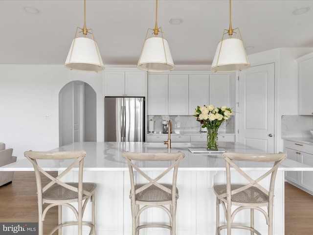 kitchen with stainless steel fridge, a breakfast bar, and white cabinets