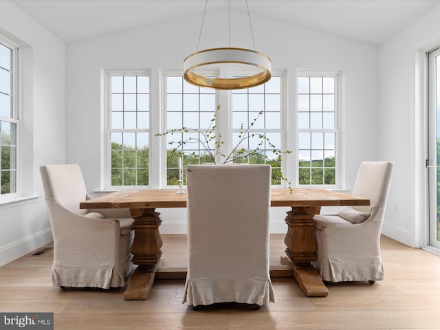 dining area featuring vaulted ceiling and light hardwood / wood-style flooring