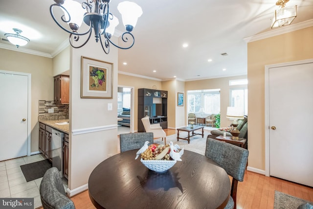 dining area with a notable chandelier, crown molding, recessed lighting, light wood-style flooring, and baseboards