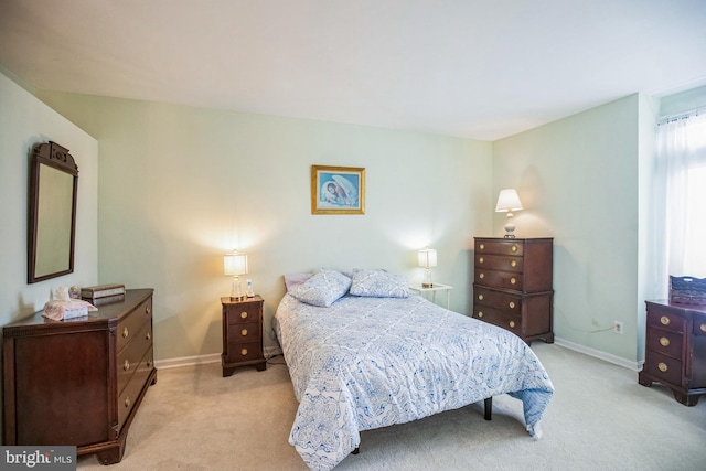 bedroom with light colored carpet and baseboards