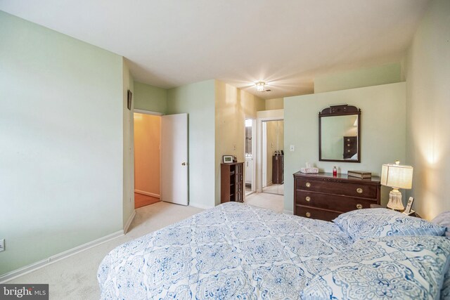 bedroom with light carpet, connected bathroom, and baseboards