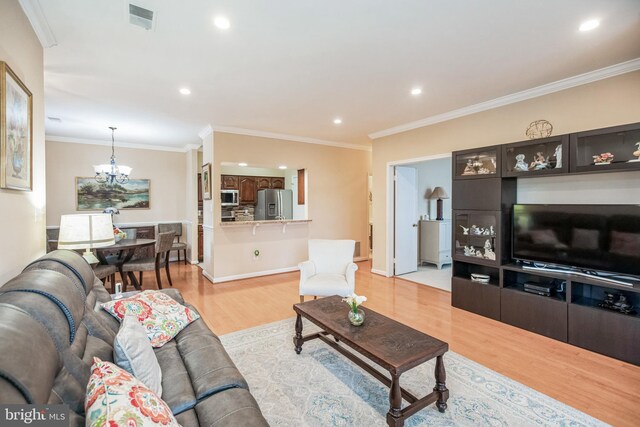 living room with crown molding, light wood finished floors, recessed lighting, visible vents, and an inviting chandelier