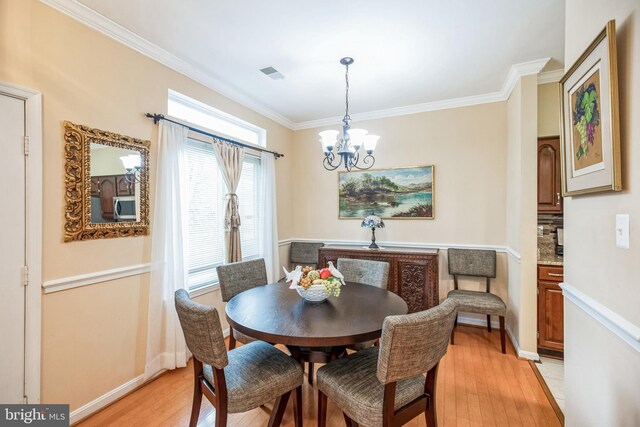 dining room featuring a notable chandelier, visible vents, baseboards, ornamental molding, and light wood finished floors