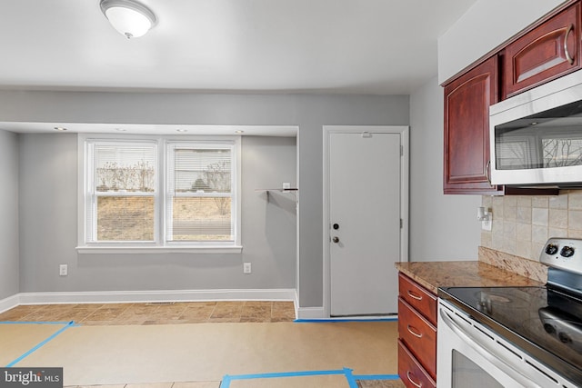 kitchen featuring reddish brown cabinets, tasteful backsplash, appliances with stainless steel finishes, and baseboards