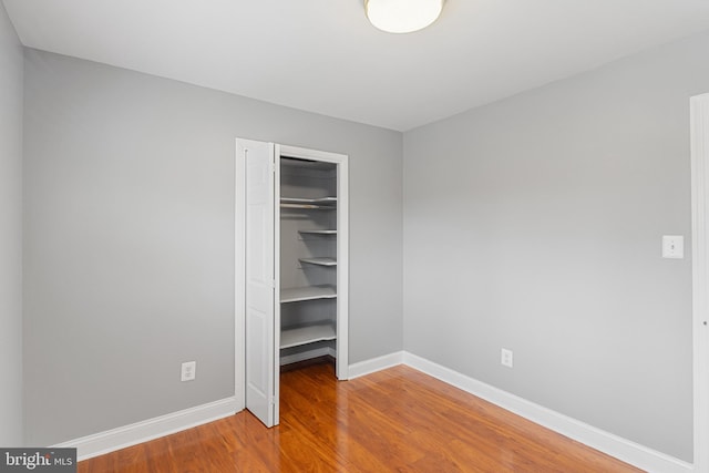 unfurnished bedroom with a closet, baseboards, and wood finished floors