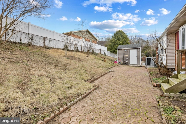 view of yard with a shed, a fenced backyard, and an outbuilding