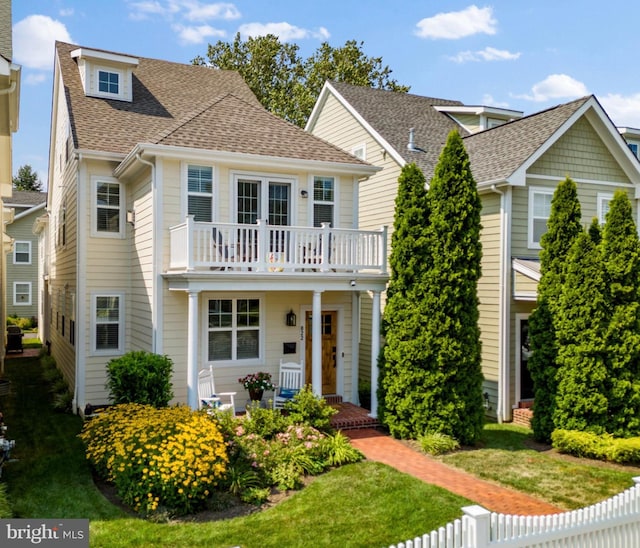 view of front of house with a balcony, covered porch, and a front lawn