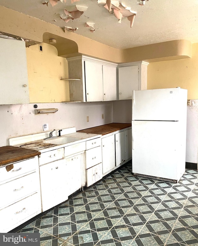 kitchen featuring wood counters, white cabinets, and white fridge