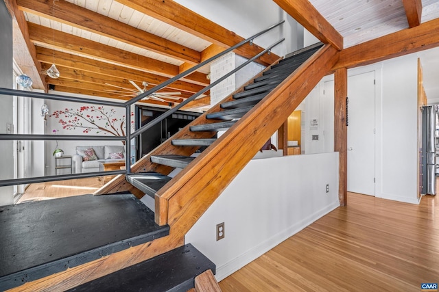 stairs with beamed ceiling, hardwood / wood-style floors, and wood ceiling