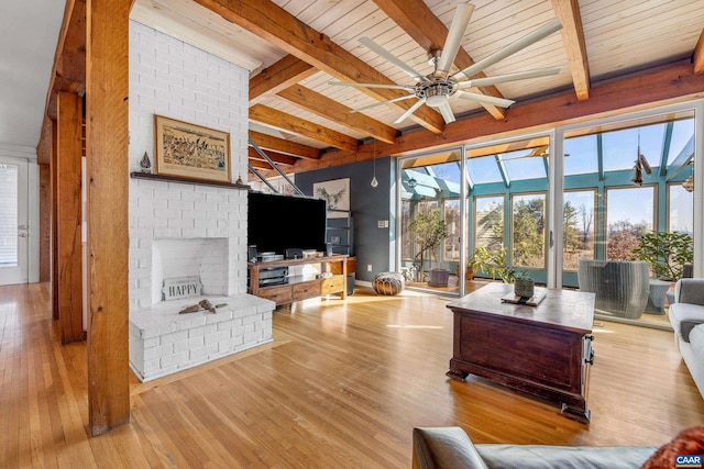 living room with light hardwood / wood-style flooring, beam ceiling, a fireplace, and a healthy amount of sunlight