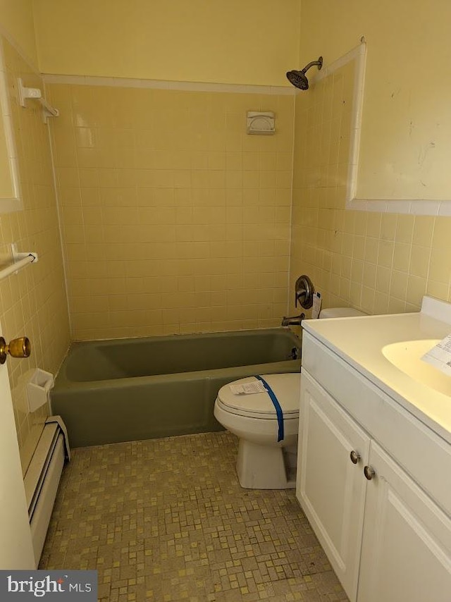 full bathroom featuring tiled shower / bath, tile walls, vanity, a baseboard heating unit, and toilet