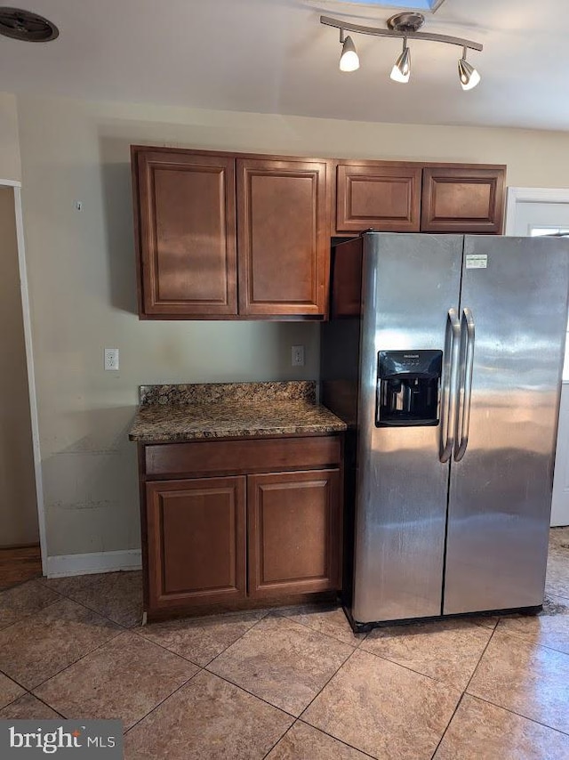 kitchen with stainless steel refrigerator with ice dispenser and dark stone countertops