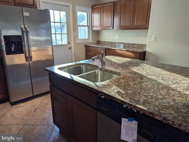 kitchen featuring light tile patterned flooring, stainless steel appliances, sink, and stone counters