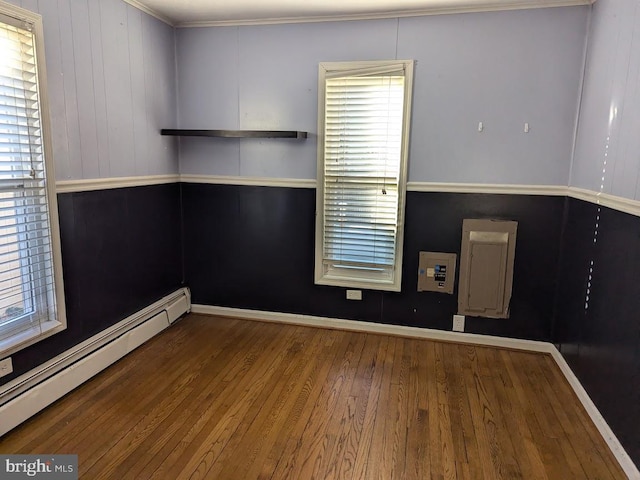 spare room featuring a baseboard heating unit and hardwood / wood-style floors