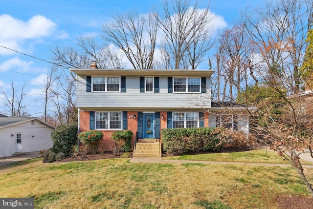 colonial-style house featuring a front yard, brick siding, and a chimney