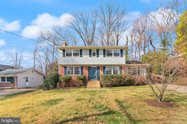 colonial inspired home with brick siding, a chimney, concrete driveway, and a front yard