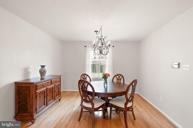 dining space with light wood finished floors, a chandelier, and baseboards