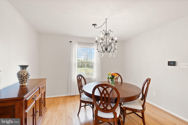 dining area with baseboards, an inviting chandelier, and light wood finished floors