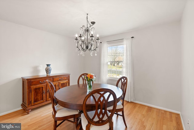 dining area with light wood finished floors, a chandelier, and baseboards