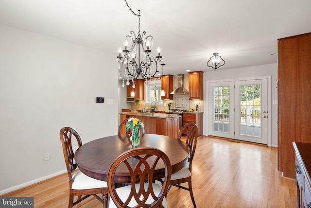 dining area with a notable chandelier, baseboards, and light wood-type flooring