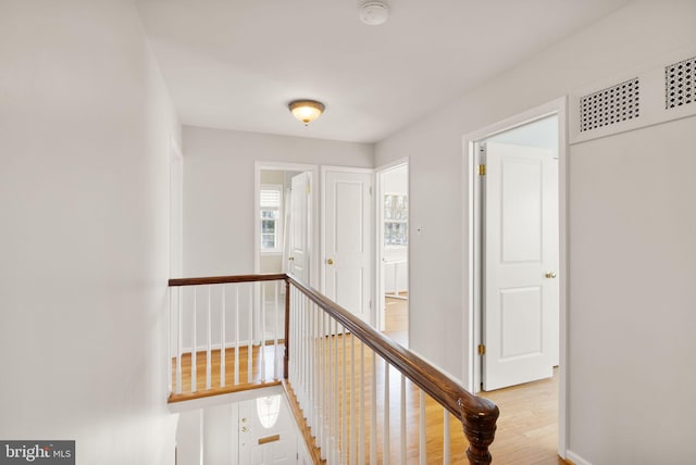 corridor featuring an upstairs landing, visible vents, baseboards, and light wood-style floors