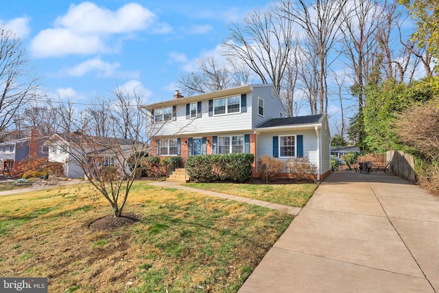 colonial home with a front lawn, concrete driveway, a chimney, and fence