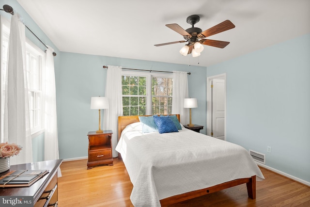 bedroom with light wood-type flooring, visible vents, baseboards, and a ceiling fan