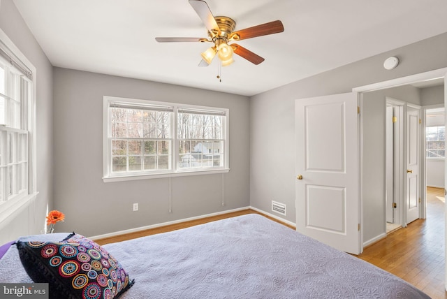 bedroom with visible vents, multiple windows, baseboards, and wood finished floors