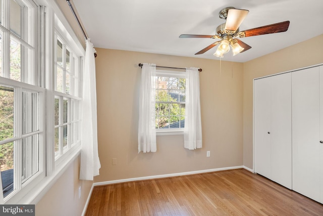 unfurnished bedroom featuring a closet, baseboards, light wood finished floors, and ceiling fan