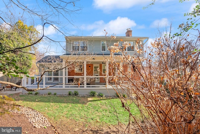 view of front of property with a front lawn, a porch, and a chimney