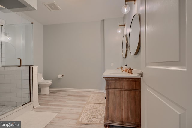 bathroom featuring vanity, hardwood / wood-style flooring, a shower with door, and toilet