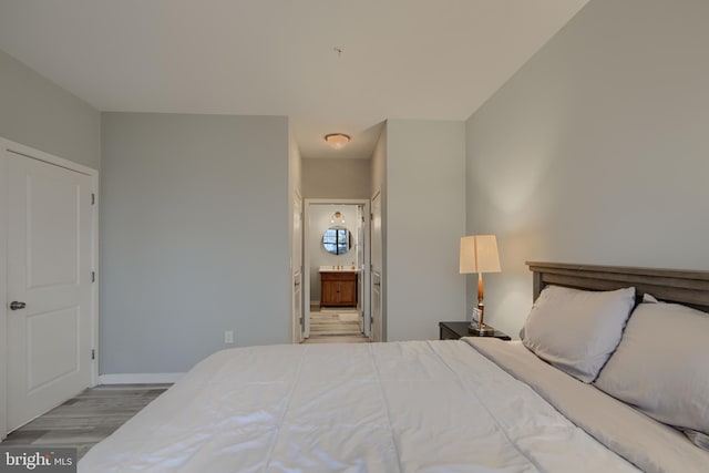 bedroom with connected bathroom and light hardwood / wood-style flooring