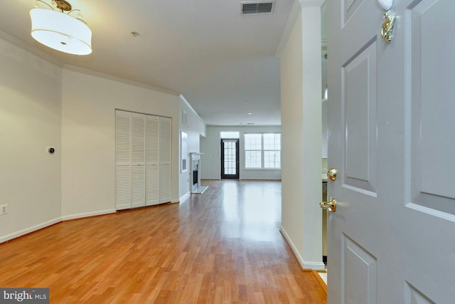 foyer with light wood finished floors, baseboards, visible vents, crown molding, and a fireplace