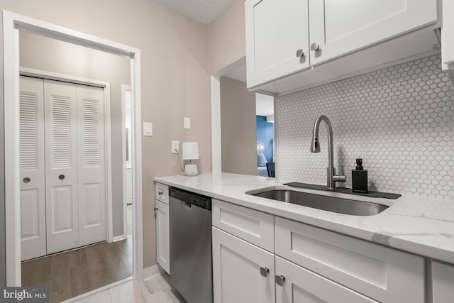 kitchen with sink, light stone counters, white cabinetry, dishwasher, and backsplash