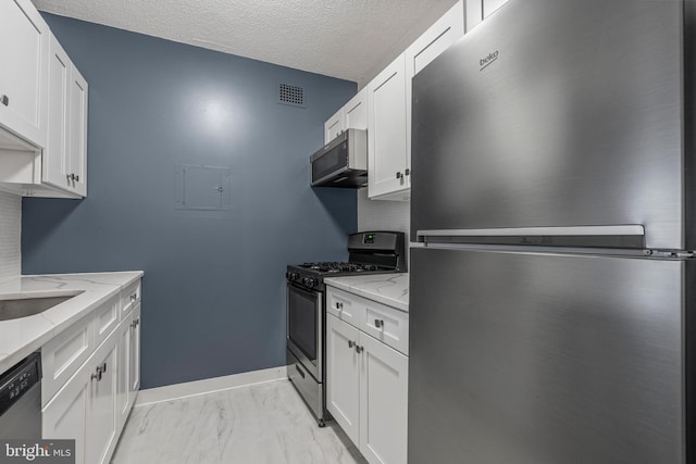 kitchen featuring light stone counters, stainless steel appliances, a textured ceiling, and white cabinets